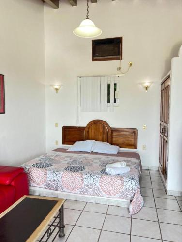 a bedroom with a bed and a red couch at Bungalows El Mirador in Cruz de Huanacaxtle