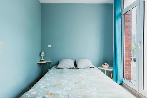 a bed in a room with a blue wall at Appartement - Michelet in Le Havre