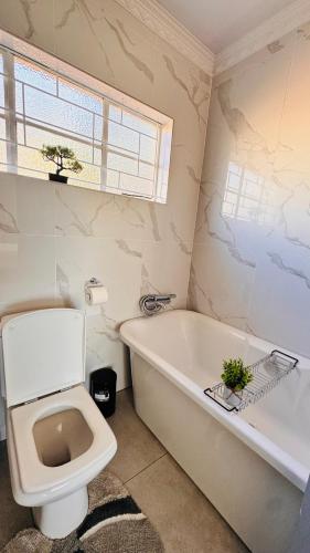 a bathroom with a toilet and a tub and a sink at Jwalaboholo Mountain View Guest House in Ficksburg