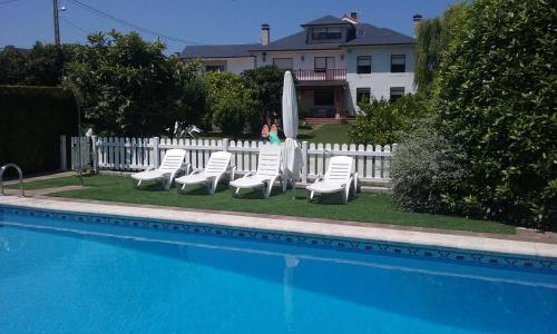 a group of white lounge chairs next to a pool at Apartamento Pueblo De Mogro in Mogro