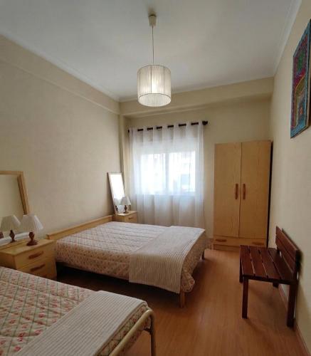 a bedroom with two beds and a table and a window at Gaivota Erudita in Buarcos