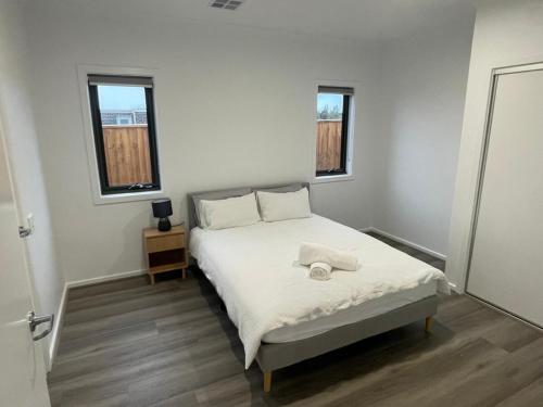 a bedroom with a bed with white sheets and two windows at Darley Retreat in Darley