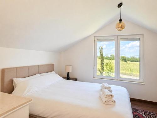 a bedroom with a white bed and a window at Vila Dinka in Lipovac