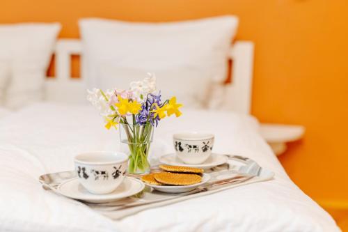 a tray with two cups and flowers on a bed at B&B Gösselsdorfer Seeblick in Sittersdorf