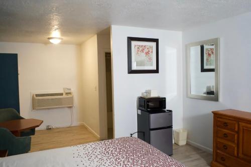 a bedroom with a bed and a desk and a microwave at Juniper Motel Madras in Madras