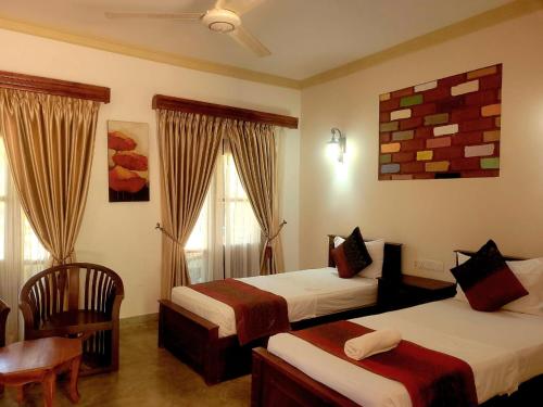 a hotel room with two beds and a table and chair at Vintara Wild Hambanthota in Hambantota