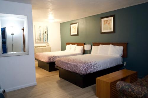 a hotel room with two beds and a chair at Juniper Motel Madras in Madras