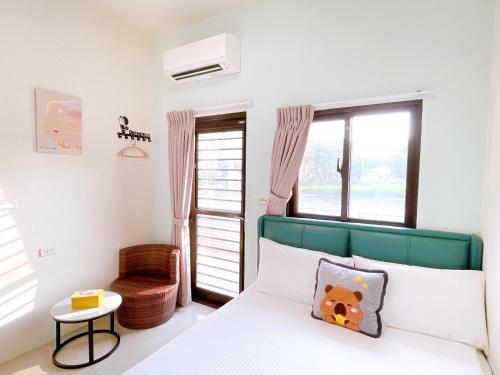 a bedroom with a bed with a green headboard and a window at Happiness blossoms Homestay in Wujie
