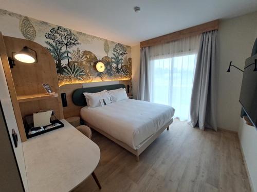 a hotel room with a bed and a window at KYRIAD PRESTIGE - PIERRELATTE in Pierrelatte