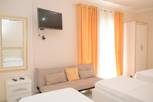 a living room with a couch and a tv on the wall at Vila Vitoria in Shëngjin
