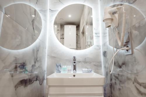 a white bathroom with a sink and a mirror at barasport city apartments in Kyiv