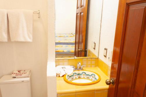 a bathroom with a sink and a mirror and a toilet at Hotel Dainzu in Oaxaca City