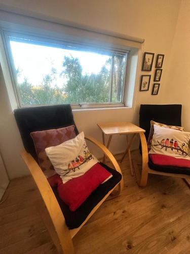 a room with two chairs and a table and a window at Casita Bosque-Rucalemu in Valdivia