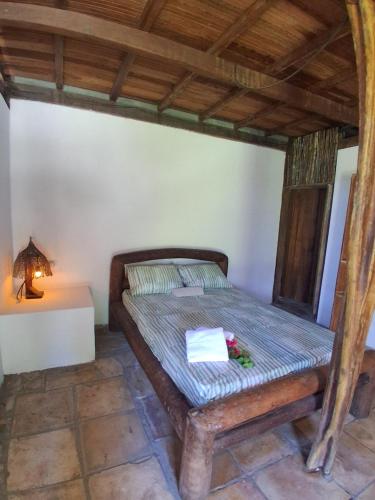 a bedroom with a bed and a table with a lamp at Bicho Grilo Hostel in Atins