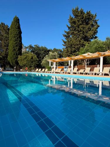 a swimming pool with chairs and blue water at KATIA BEACH Holiday Cottage in Kassiopi