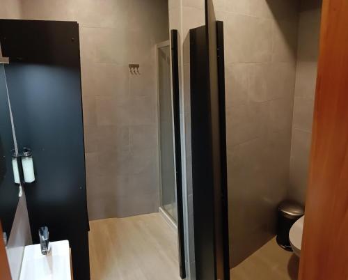 a bathroom with a shower with a toilet and a sink at Santa Alegria Hostel in Ponta Delgada