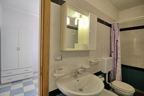 bagno con lavandino, servizi igienici e specchio di Mansarda Canarina a Marina di Pescoluse