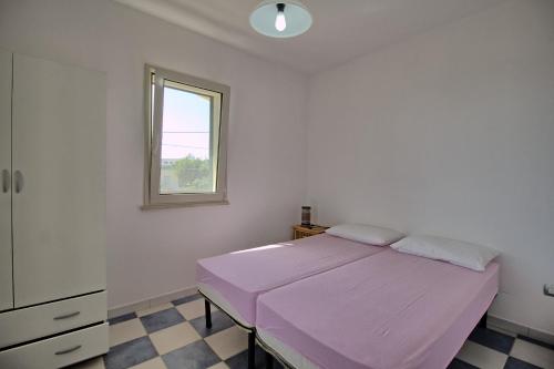 una camera con letto rosa e finestra di Mansarda Canarina a Marina di Pescoluse