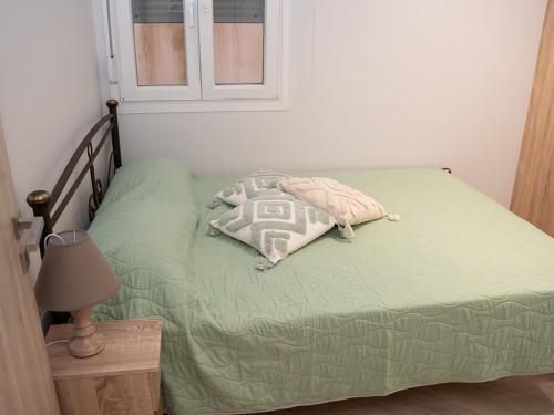 a bed with a green comforter and a pillow on it at Meltemi Apartment in Chios