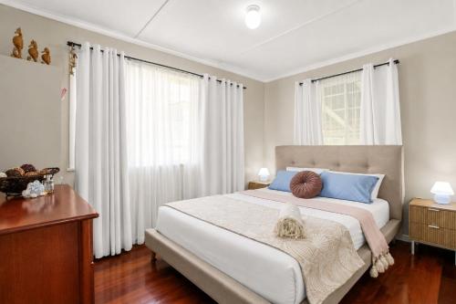 a bedroom with a large bed with white curtains at Kitchener Street 2, Golden Beach in Golden Beach
