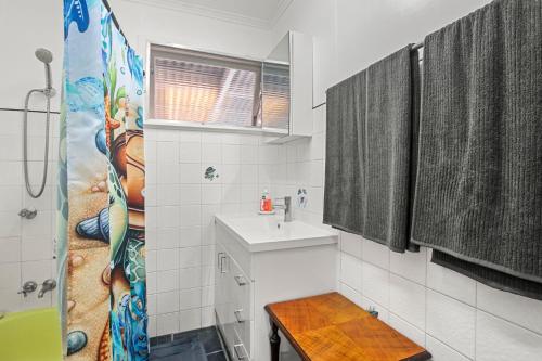 a white bathroom with a sink and a shower at Kitchener Street 2, Golden Beach in Golden Beach