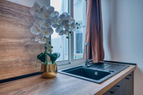 a vase of flowers sitting on a counter next to a sink at St Julian s Luxury Laura Apartments in Is-Swieqi