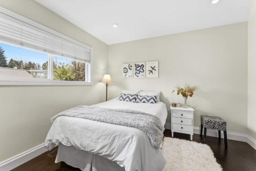 a white bedroom with a bed and a window at Bright Coquitlam Home & Spacious Backyard in Coquitlam