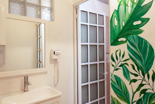 ein Badezimmer mit einem weißen Waschbecken und einem Spiegel in der Unterkunft La Selva Hostel in Mexiko-Stadt