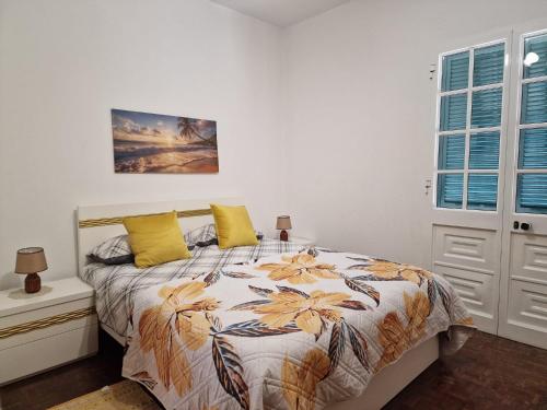 a bedroom with a bed with yellow pillows at Sol e Mar by the airport in Santa Cruz