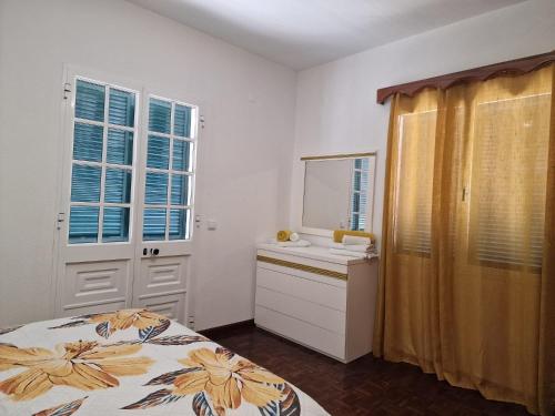 a bedroom with a bed and a sink and a mirror at Sol e Mar by the airport in Santa Cruz