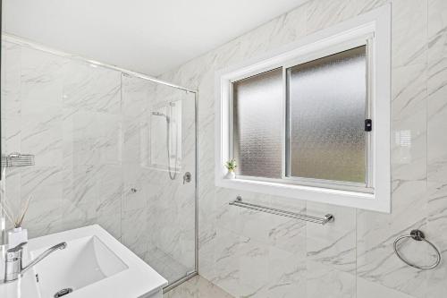 a bathroom with a shower and a sink and a window at Mariners in the Village in Shellharbour