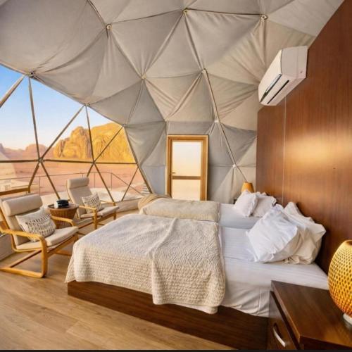 a bedroom with a tent with a bed and chairs at WADI RUM ROTANA BUBBLE lUXURY in Wadi Rum