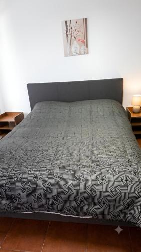 a bed with a black and white comforter on it at Dpto céntrico en primer piso in Valdivia