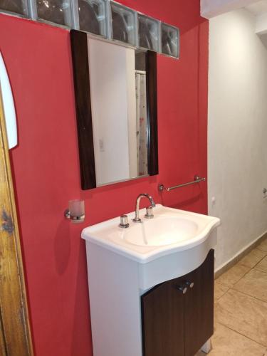 a bathroom with a white sink and a red wall at El Encuentro in Sierra de los Padres