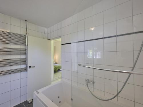 a white tiled bathroom with a shower and a tub at Brabants licht in Lage Mierde