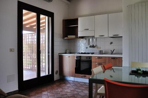 a kitchen with white cabinets and a table and a window at Azienda Agrituristica Il Giuggiolo in Principina a Mare