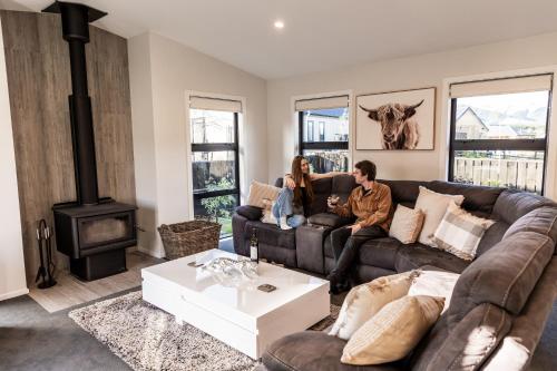 a man and woman sitting on a couch in a living room at Alpine | BBQ & Fireplace | Table Tennis - HS68319 in Hanmer Springs