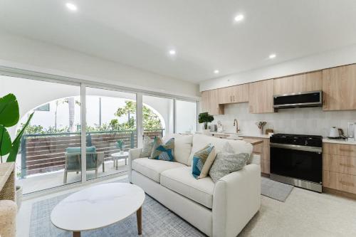 a living room with a white couch and a kitchen at The Reserve - Boca Designer Pool Suite in Boca Raton