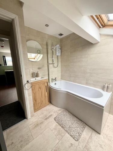 a large bathroom with a tub and a sink at Aire House, Keighley in Keighley