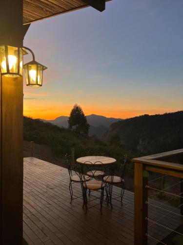 a table and chairs on a deck with the sunset at Chalé Pazinato in Venda Nova do Imigrante