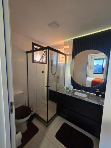 a bathroom with a shower and a toilet and a mirror at Vista Mar Icaraí Ingá in Niterói