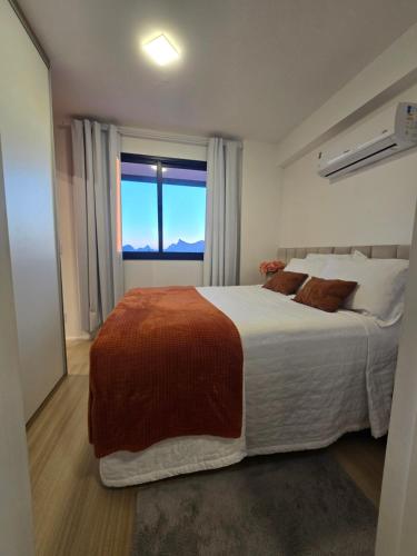 a bedroom with a large bed with a large window at Vista Mar Icaraí Ingá in Niterói