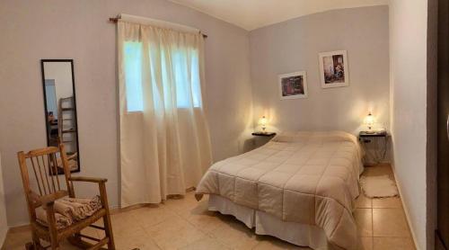 a bedroom with a bed and a chair and a window at La Casita de la Granja, Casa con Pileta Y Gran Parque in La Granja