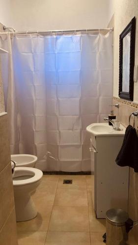 a white bathroom with a toilet and a sink at La Casita de la Granja, Casa con Pileta Y Gran Parque in La Granja
