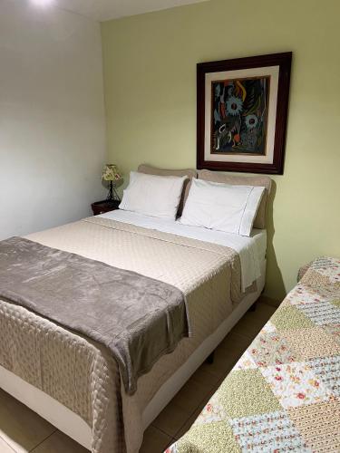 a bedroom with a bed and a picture on the wall at Pousada Luar e Serenata in Conservatória