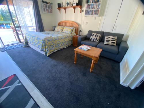 a room with a bed and a couch and a table at Union Street Hideaway in Waihi