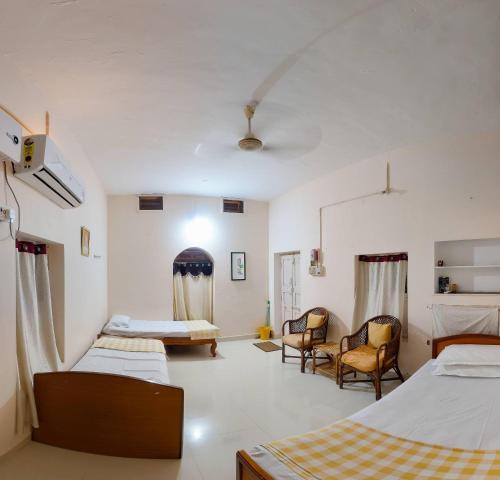 a room with two beds and two chairs in it at Sri Anantha Niketan Ashram in Tiruvannāmalai