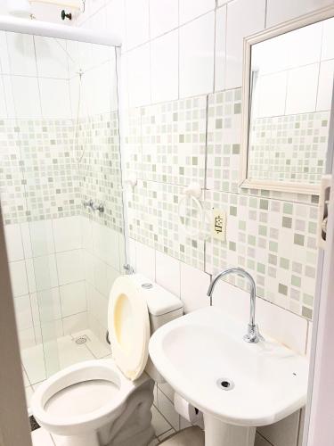 a white bathroom with a toilet and a sink at Pousada Luar e Serenata in Conservatória
