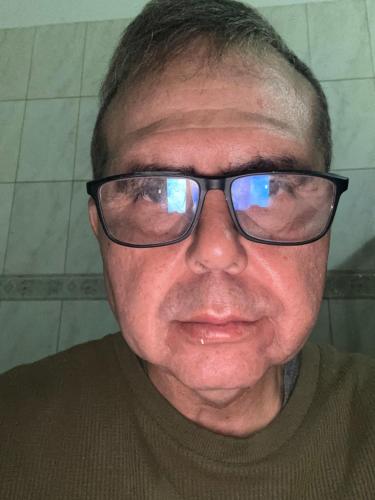 a man wearing glasses is smiling at the camera at Apartamento in Ribeirão Preto