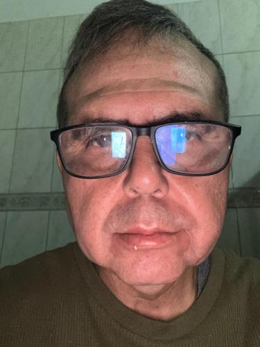 an older man wearing glasses with reflections in his eyes at Apartamento in Ribeirão Preto